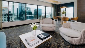 A modern hotel room with large windows, a city view, a dining area, and a cozy seating arrangement. - SO/ Auckland (Auckland)