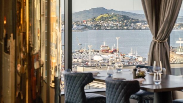 A dining area with a view of a harbor and a mountain. - SO/ Auckland (Auckland)