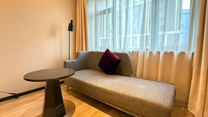 Ein modernes Hotelzimmer mit einer Couch, einem kleinen runden Tisch und einer Stehlampe.