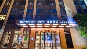 Ein hohes Hotelgebäude mit beleuchteten vertikalen Linien und einem Schild mit der Aufschrift 'Mercure Hotel'.