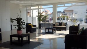 Un espace intérieur spacieux, doté d’une grande fenêtre, d’une plante en pot et d’un coin salon avec un canapé et des fauteuils.