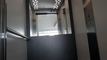 A modern elevator with a metallic finish and a series of lights on the ceiling.