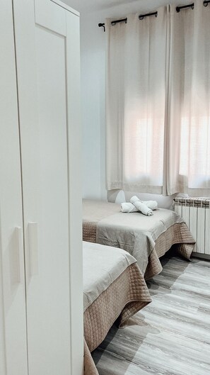 Un dormitorio con dos camas, un armario y un radiador.