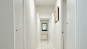 A narrow hallway with white walls and a light-colored floor, leading to a door at the end. - Hostal Ruta de Francia (Barcelona)