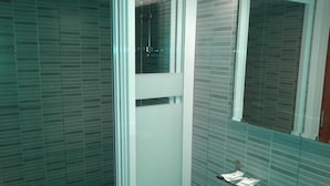 Une salle de bain avec une douche à parois de verre, un miroir et un mur carrelé.