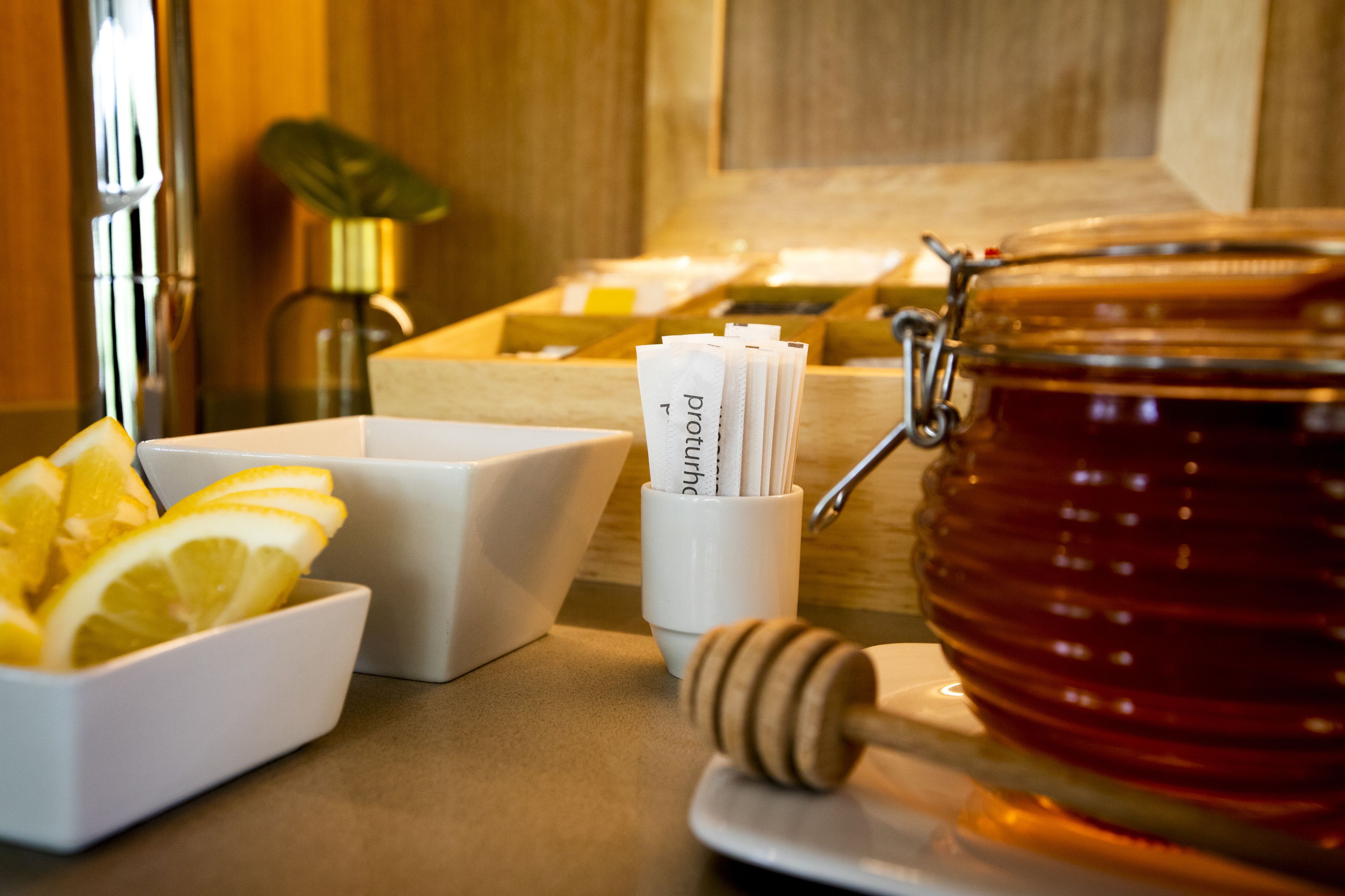 Un plan de travail de cuisine avec un pot de miel, des tranches de citron et un ustensile pour servir le miel.