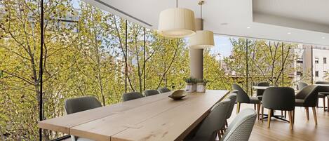 Un espace de salle à manger moderne, doté d’une longue table, de nombreuses chaises et de luminaires suspendus.