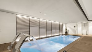 A modern indoor swimming pool with a water feature, wooden flooring, and a minimalist design. - Protur Naisa Palma Hotel (Palma de Mallorca)