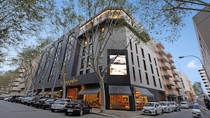 A modern building with a curved facade, multiple balconies, and a row of parked cars in front. - Protur Naisa Palma Hotel (Palma de Mallorca)