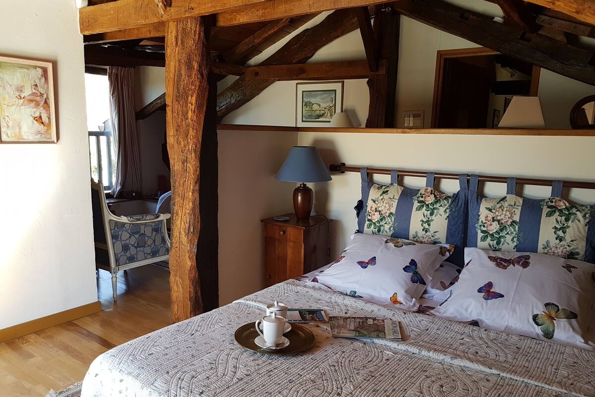 Un dormitorio con una cama, una silla de madera, una mesita de noche y una lámpara.