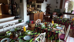 Comedor con mesas dispuestas para el desayuno, mostrando una variedad de platos y bebidas.