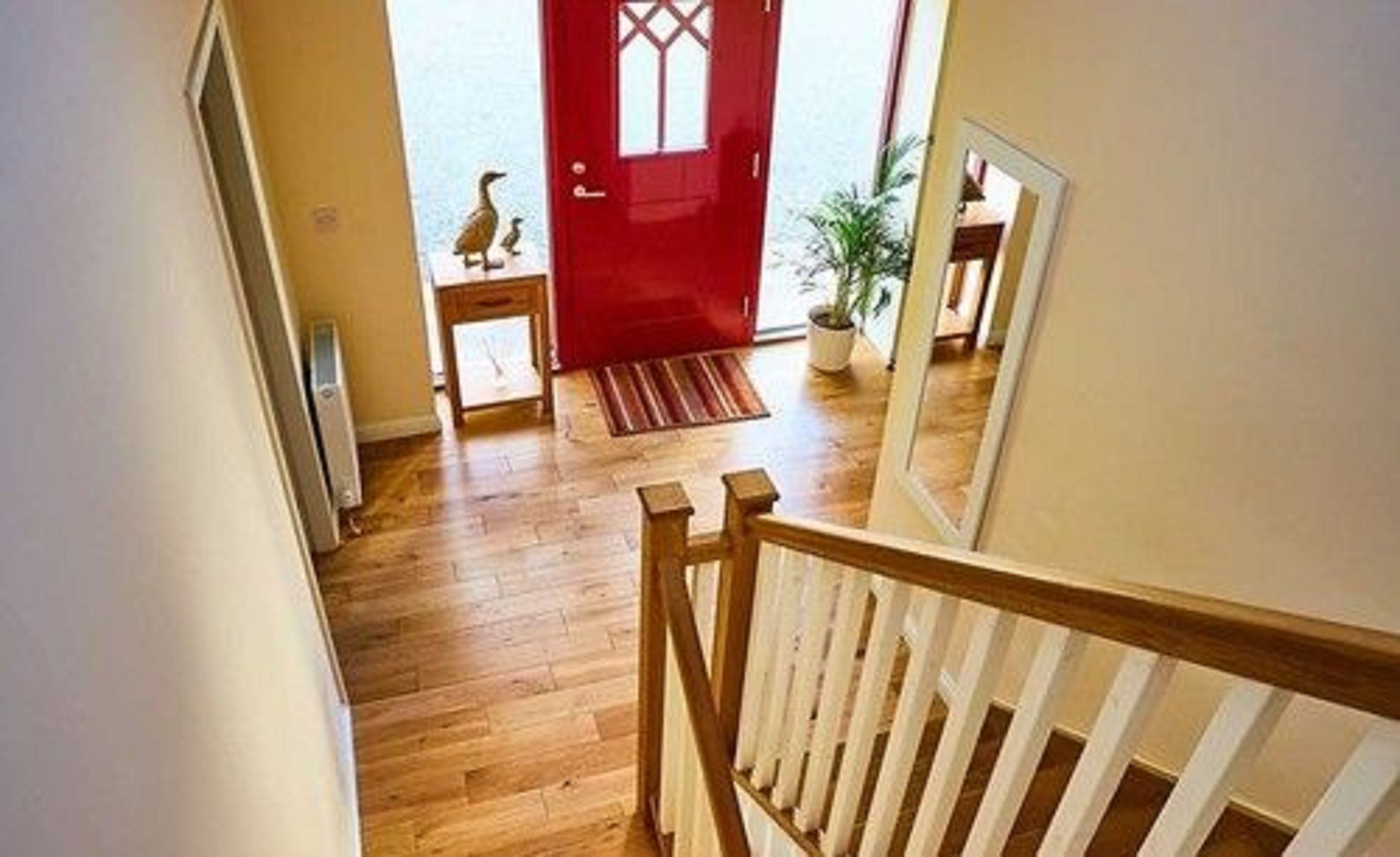 A wooden staircase with a white railing leading to a red door.