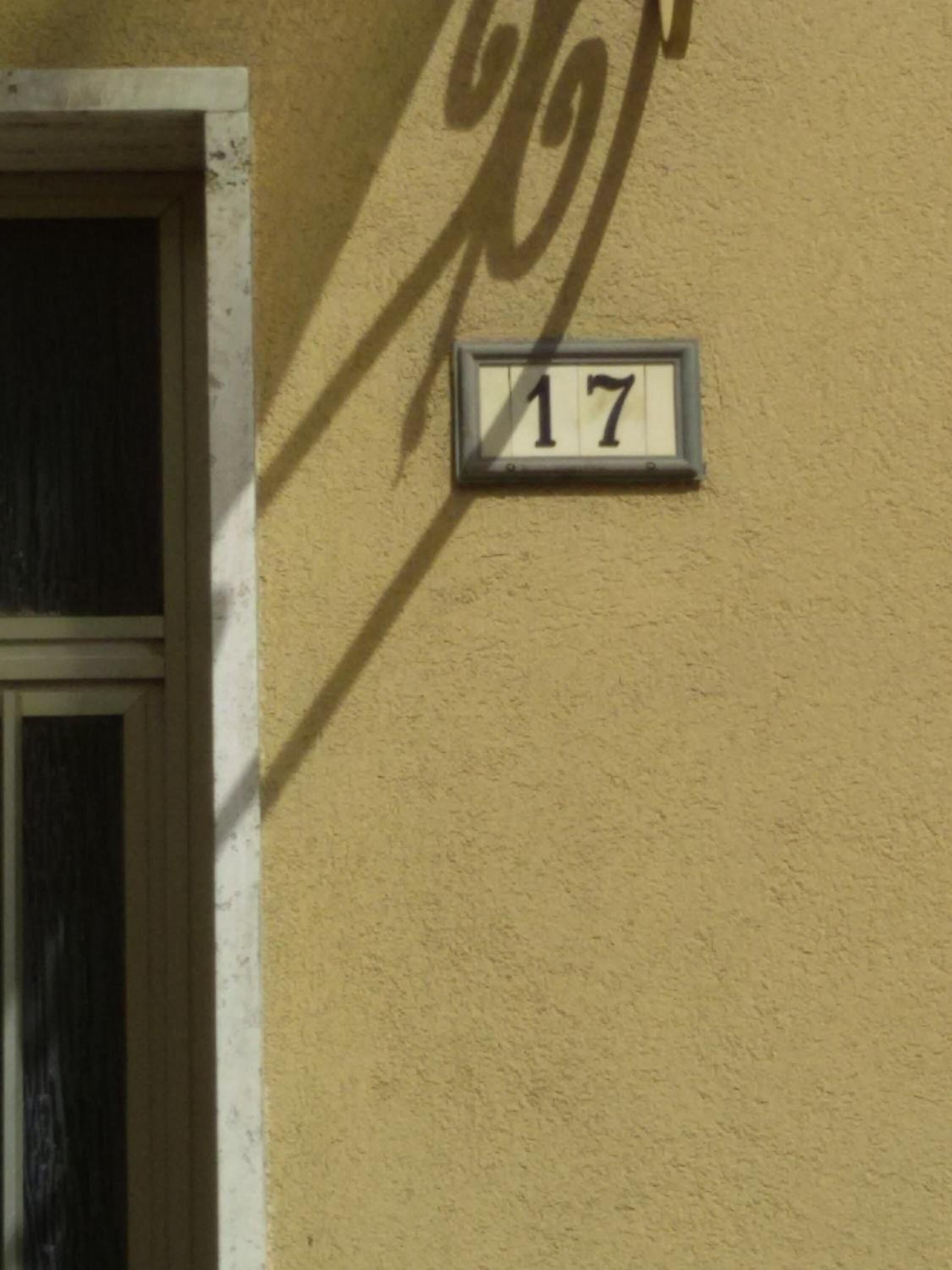 Huisnummer '17' op een gestructureerde muur.