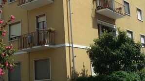 Un immeuble à plusieurs étages doté de balcons, dont certains sont ornés de plantes.