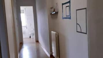 Un couloir avec un radiateur, une porte au fond et un mur orné de tableaux encadrés.