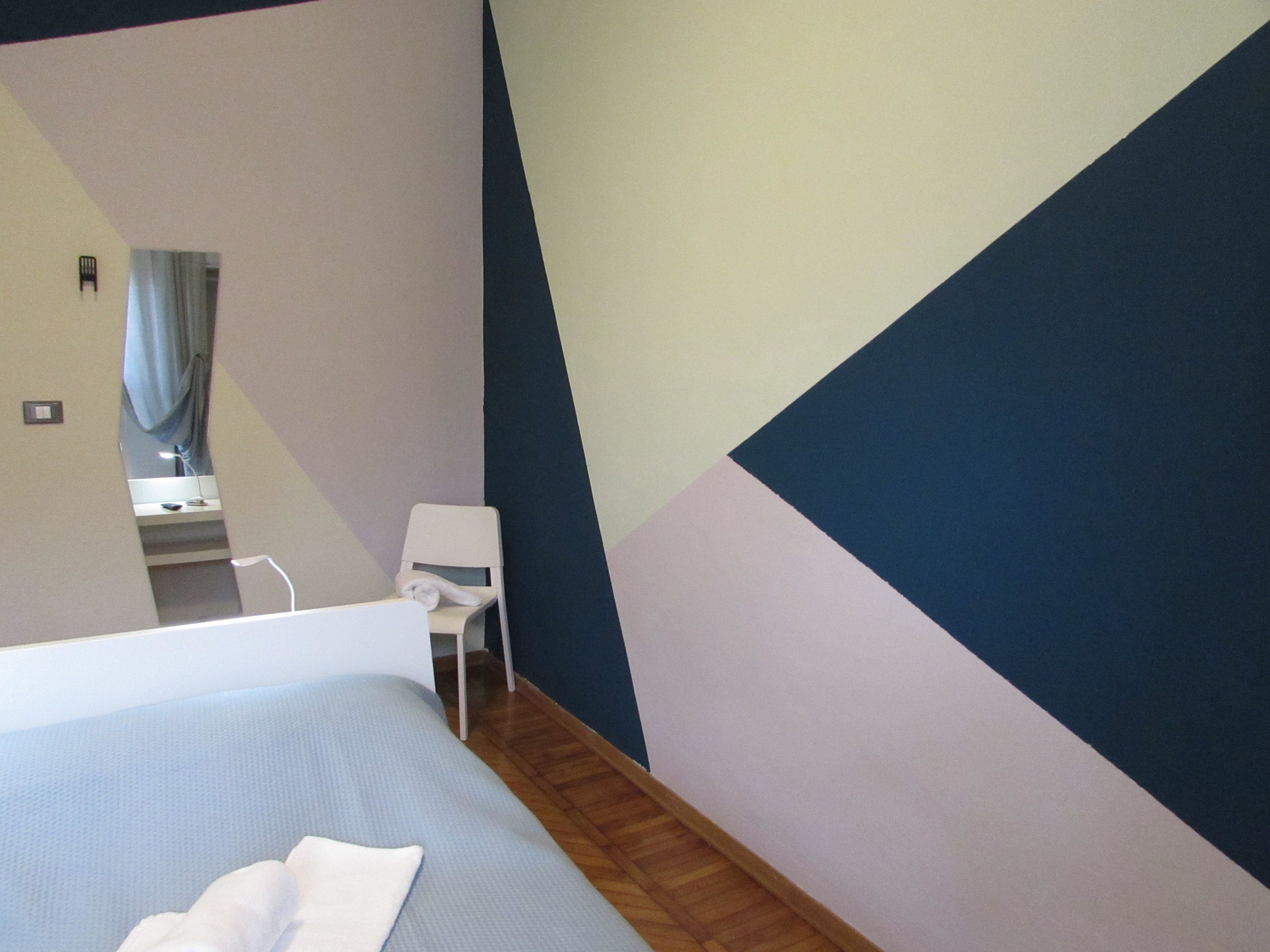 A modern hotel room with a bed, a small desk, and a chair.