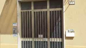 Une entrée d’immeuble avec un portail en métal, une petite boîte aux lettres et une plaque indiquant le numéro de l’immeble.