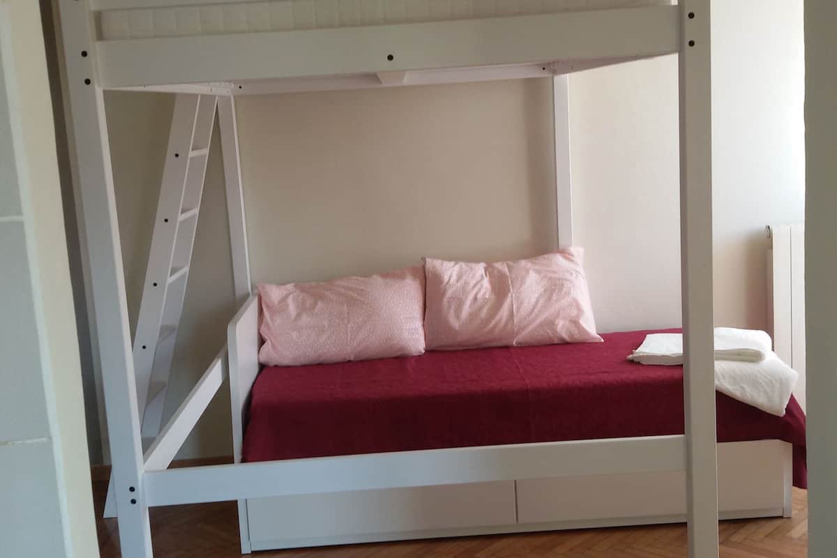 A bunk bed with a ladder, a red bedspread, and two pillows.