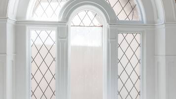Una ventana arqueada blanca con una celosía de diseño de diamante.