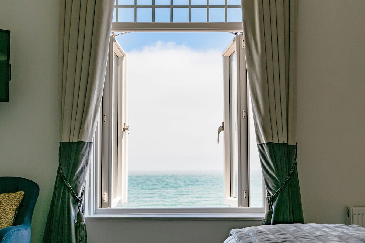 Un dormitorio con una ventana grande, una cama y una silla.