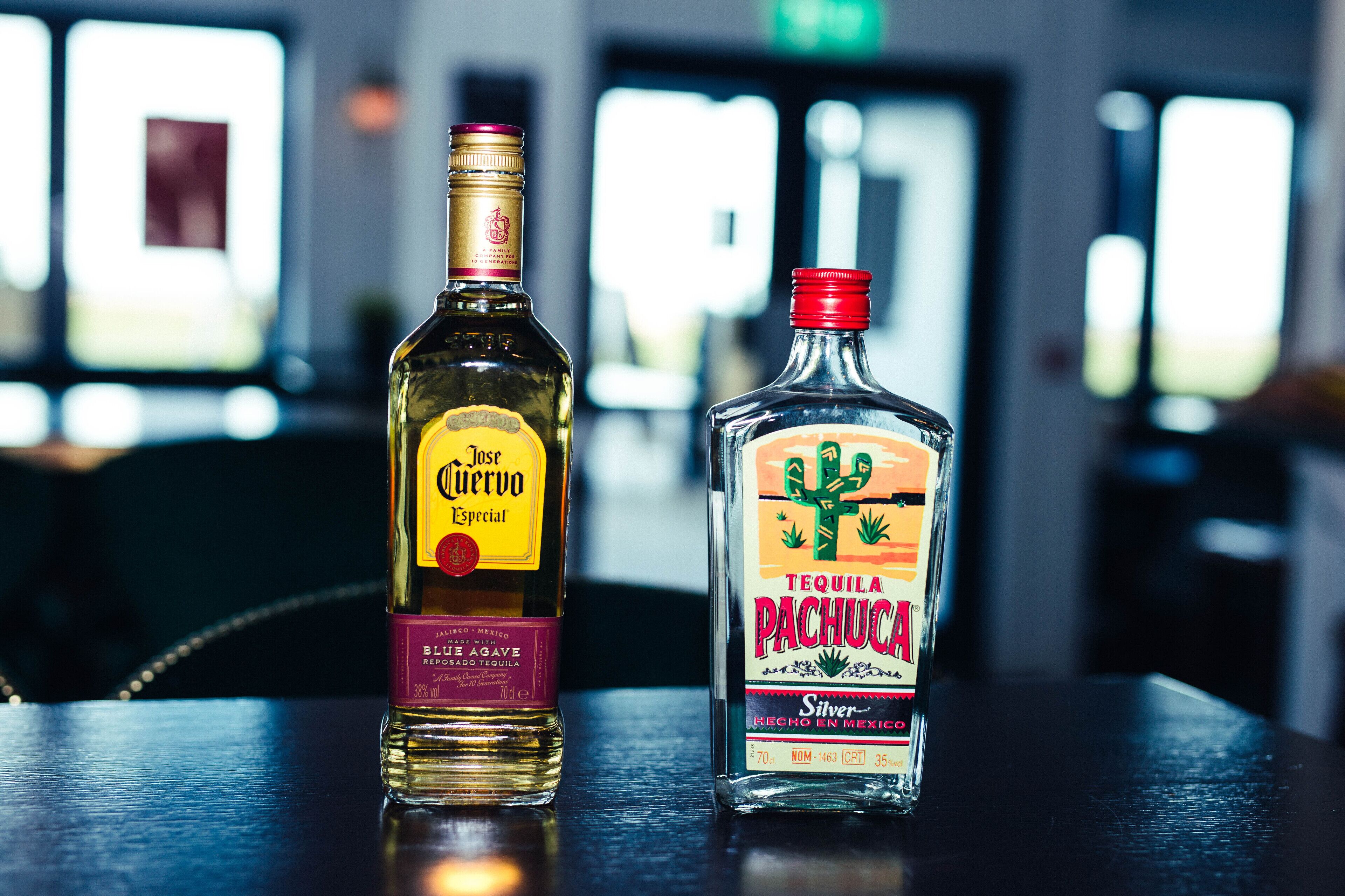 Two bottles of tequila on a table with a blurred background.