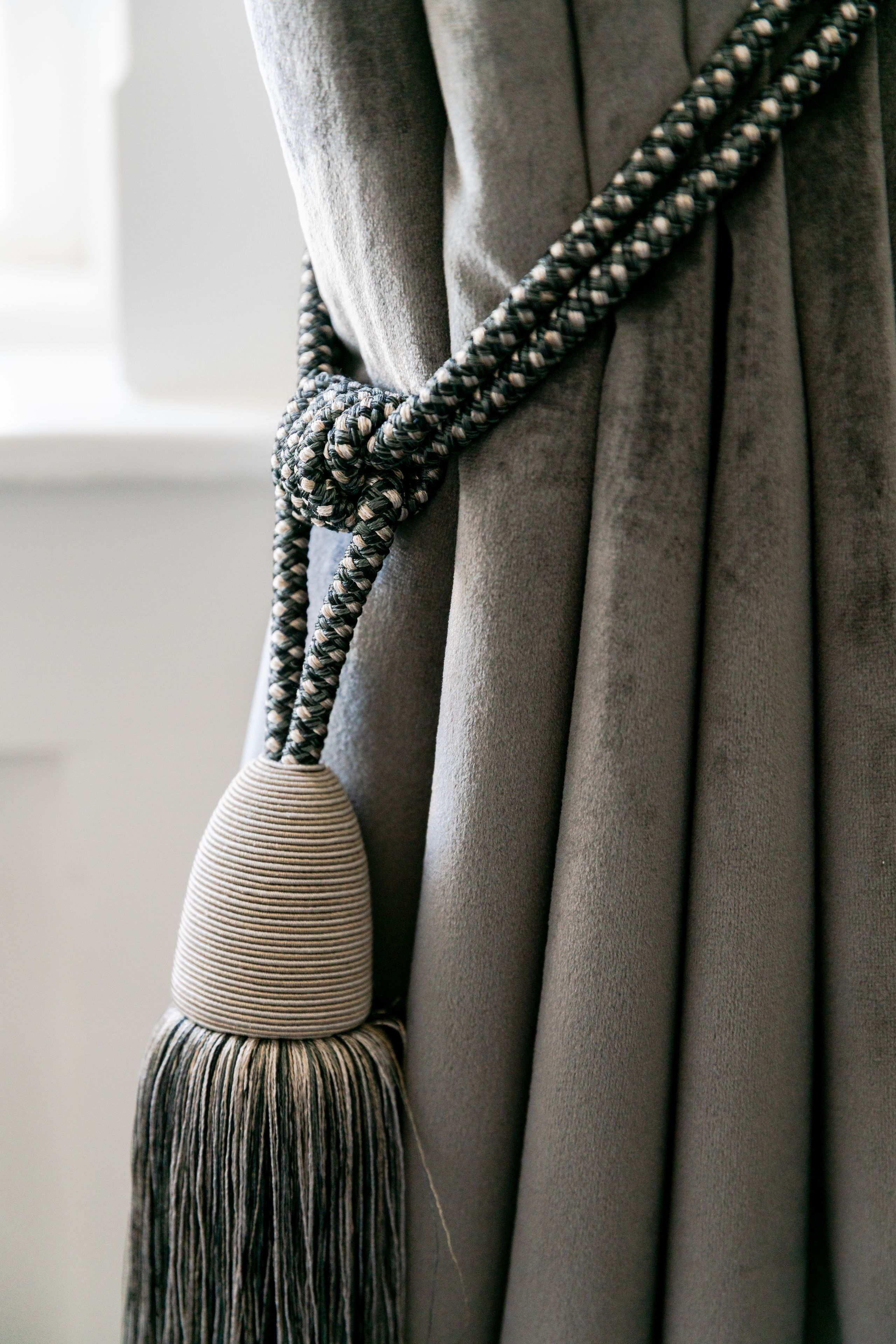 A close-up of a curtain with a braided tassel.