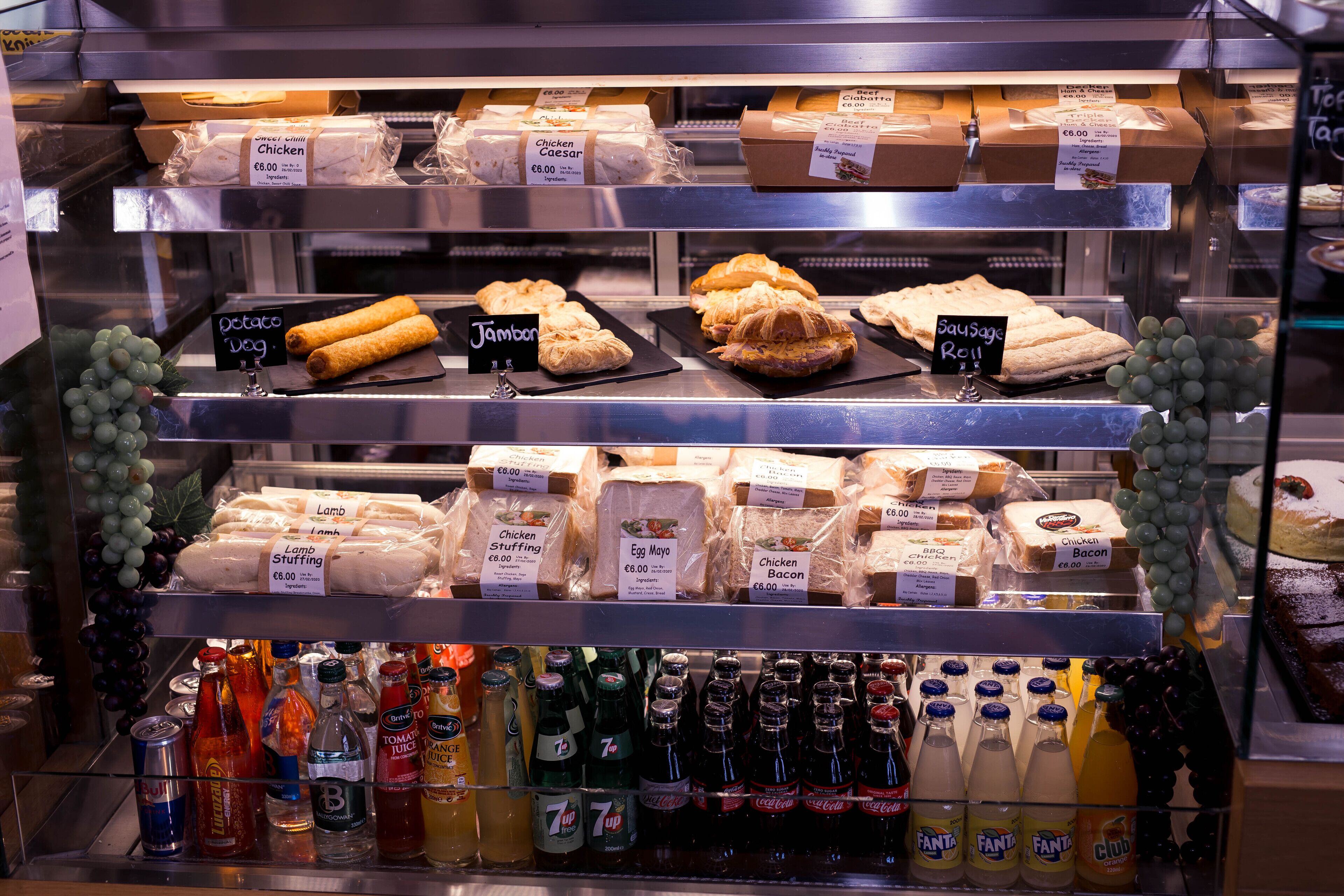 A deli display with various food items and beverages.