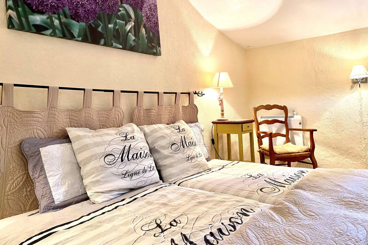 Ein Schlafzimmer mit einem Bett, zwei Nachttischen, einem Sessel und einer Wandlampe.