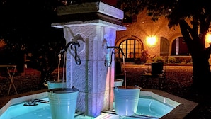 Une fontaine composée de deux seaux et d’une structure en pierre, entourée d’un bassin.