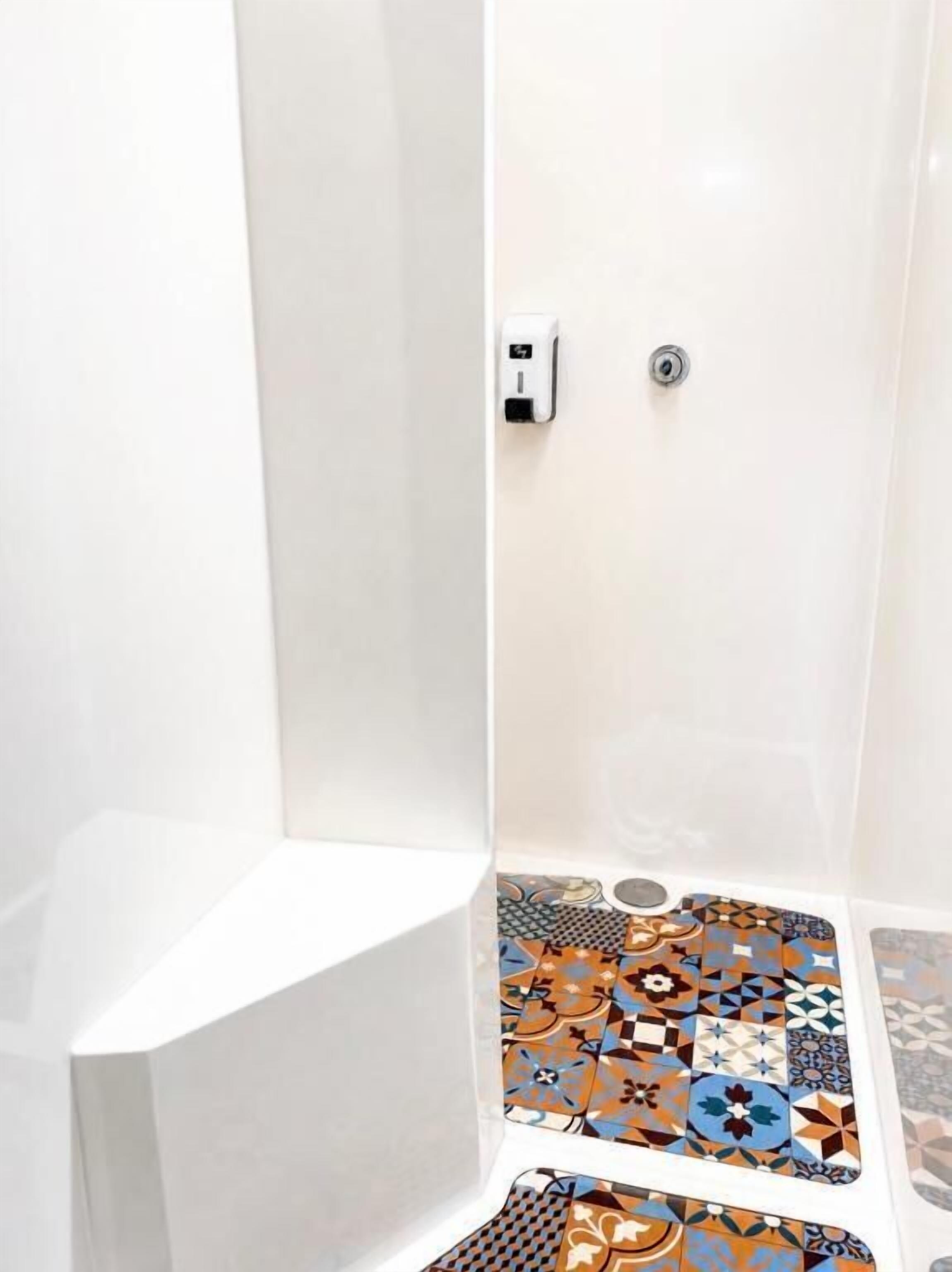 A shower with a white interior and a tiled floor featuring a geometric pattern.