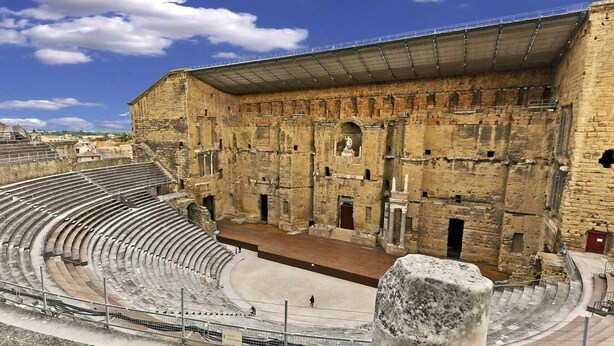 Un antiguo anfiteatro con asientos escalonados y un escenario central.
