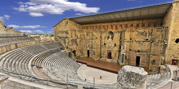 Un antiguo anfiteatro con asientos escalonados y un escenario central.