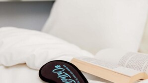 Una cama con un libro y un objeto negro con texto.