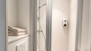 Un baño moderno con ducha de vidrio, inodoro y perchero para toallas.