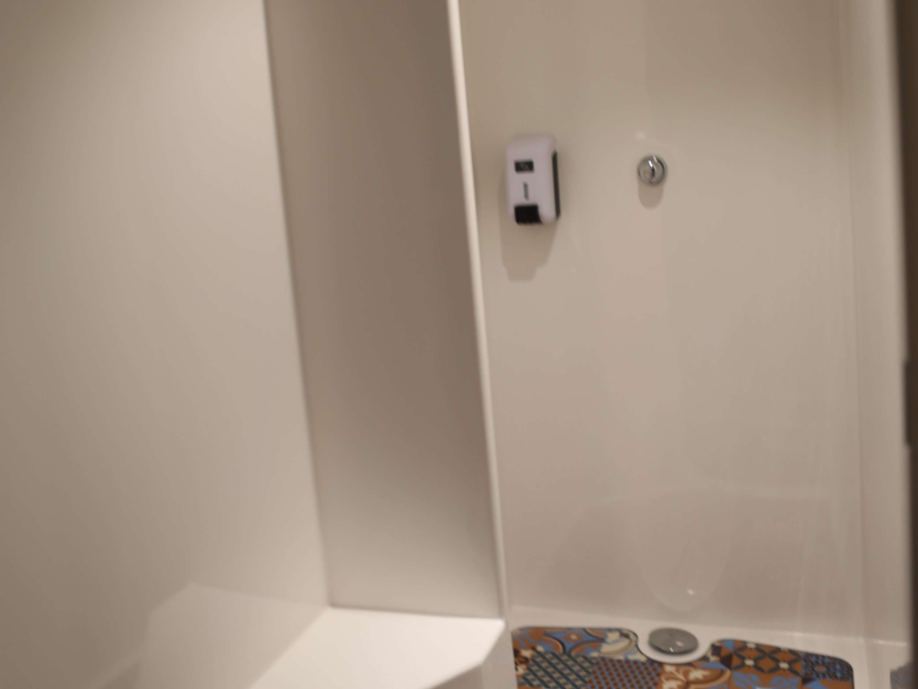 Un baño con lavamanos blanco, dispensador de jabón y un inodoro.