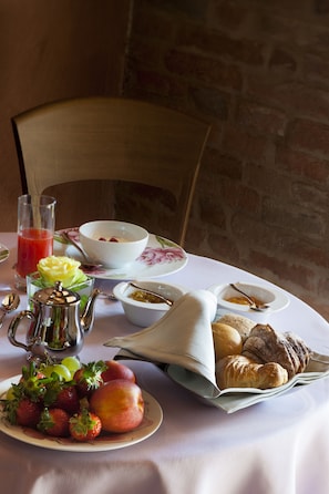 A breakfast table with a variety of food items including fruits, bread, and a glass of juice. - Villa Armena (Buonconvento)