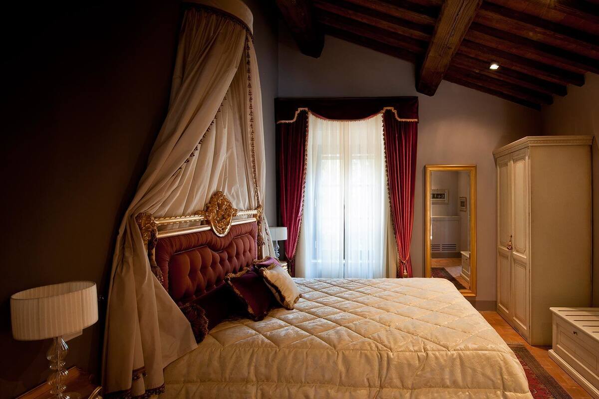 A bedroom with a four-poster bed, a canopy, a wardrobe, and a mirror.