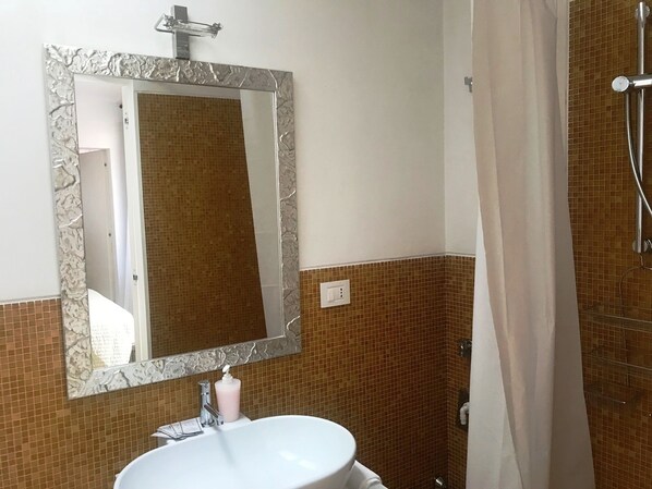 A bathroom with a white sink, a large mirror with a decorative frame, and a shower area with a curtain.