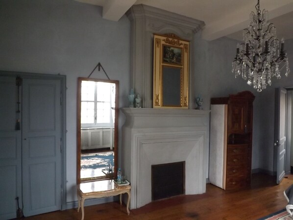Ein Zimmer mit Kamin, einem Chandelier und einem Spiegel darüber.