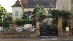 A historic building with a stone facade, a black gate, and a signboard. - Maison Porte Del Marty (Lalinde)