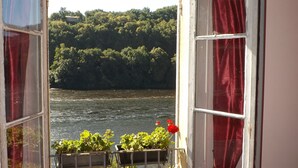 An open window with a view of a river and forested hills. - Maison Porte Del Marty (Lalinde)
