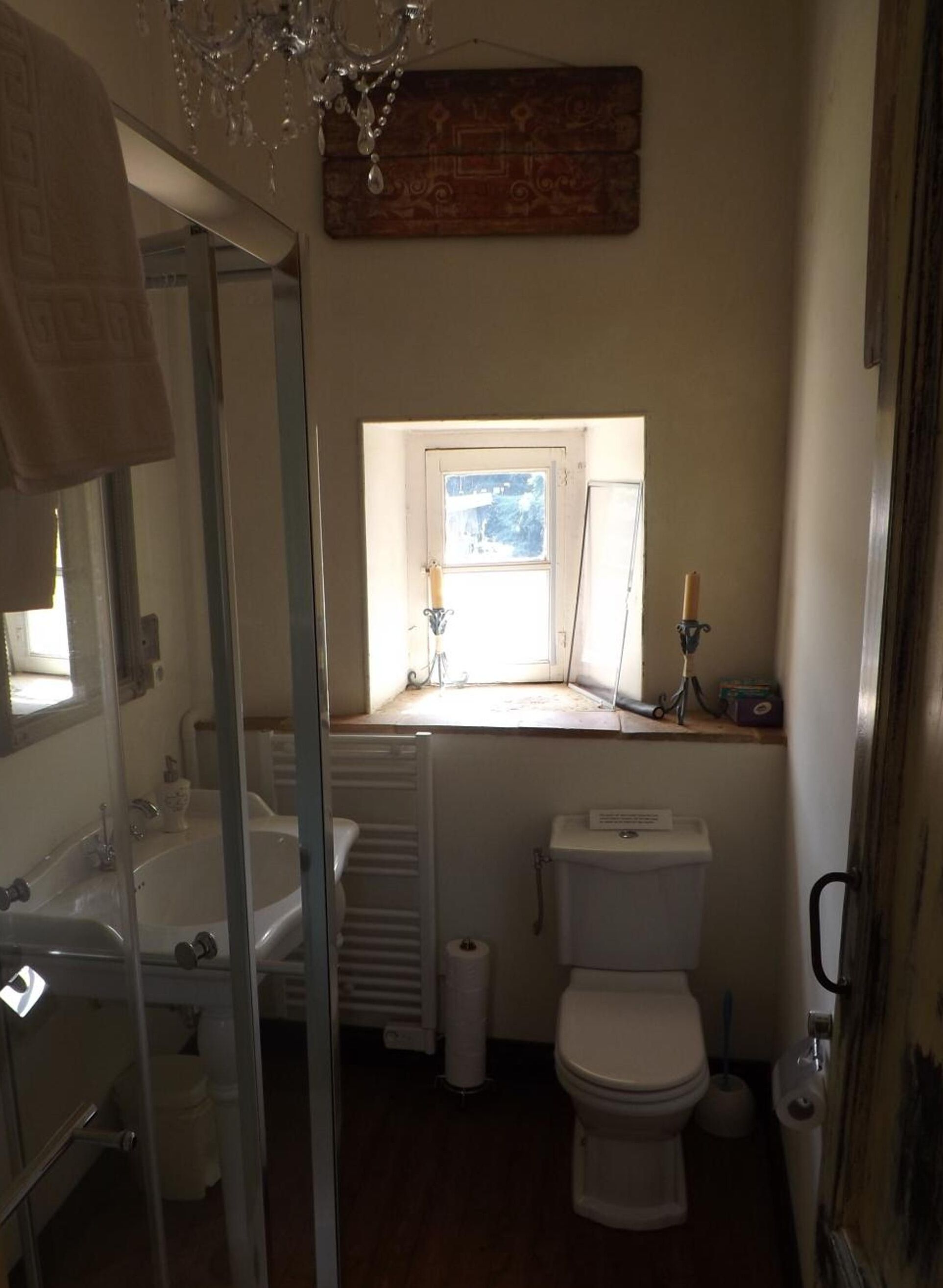 A bathroom with a window, a radiator, a toilet, and a sink.