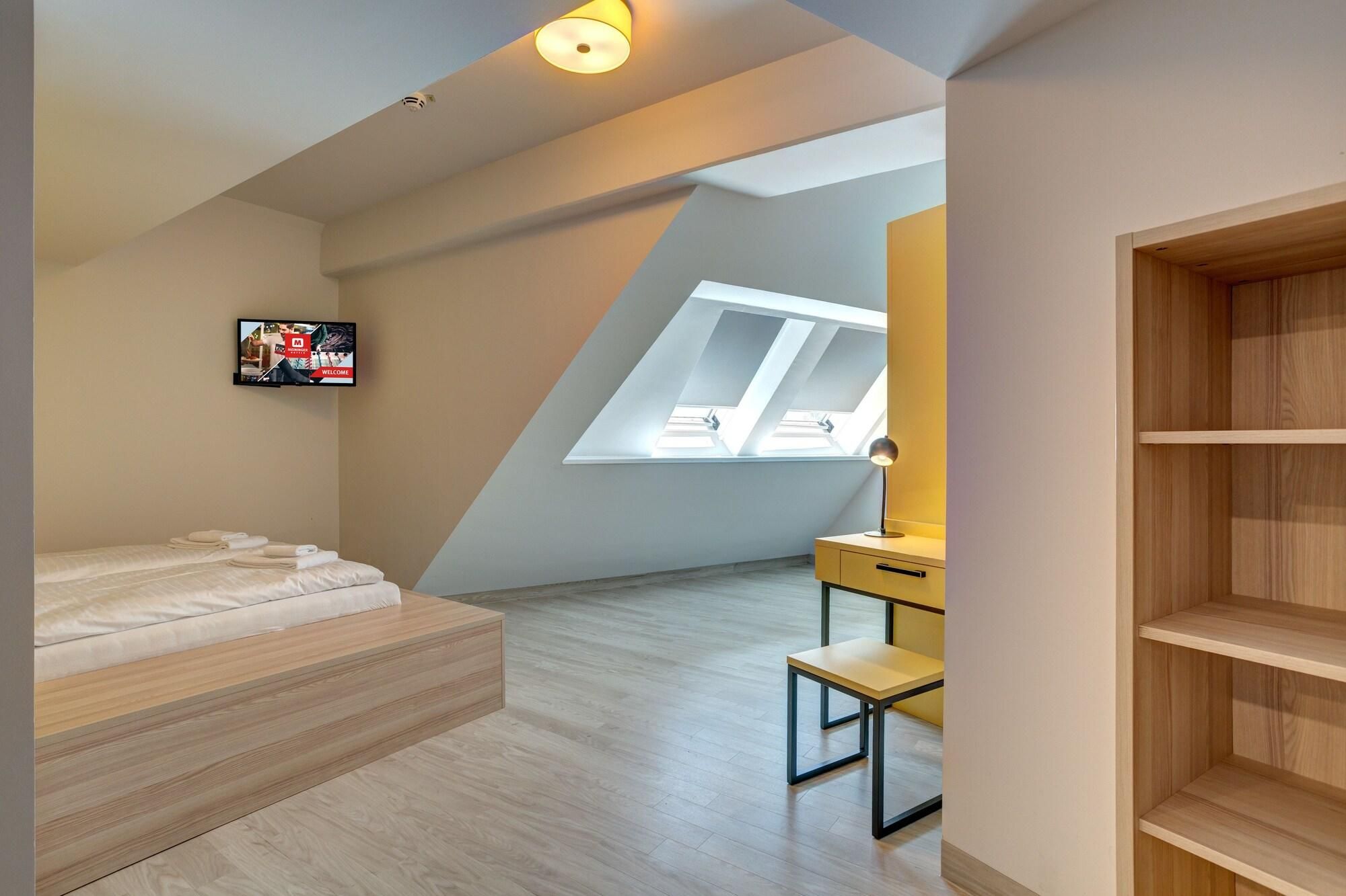 Ein modernes Schlafzimmer mit schrägen Wänden, einem Bett, einem Schreibtisch und einem an der Wand befestigten Fernseher.