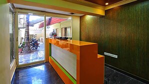 A reception area with a glass door leading outside, a reception desk, and a wooden wall. - Vinodhara Guesthouse (Tirukalukundram)