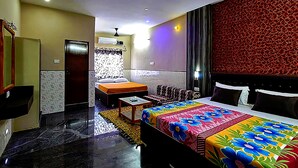 A hotel room with a bed, a sofa, a small table, and a mirror. - Vinodhara Guesthouse (Tirukalukundram)