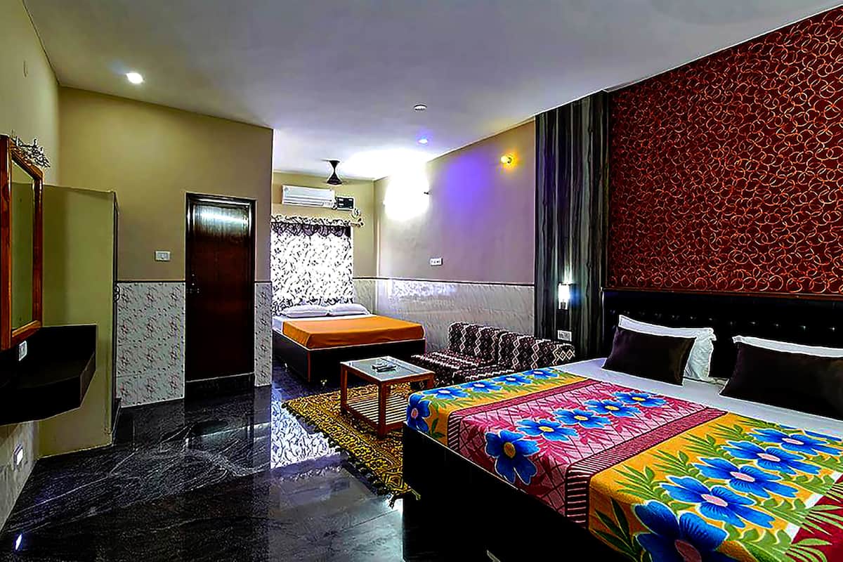 Quarto de hotel com uma cama, um sofá, uma mesinha e um espelho.
