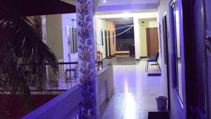 A hallway with a tiled floor, a railing on one side, and a door on the other. - Vinodhara Guesthouse (Tirukalukundram)