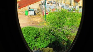 Vista a través de una ventana de un pueblo rural con edificios tradicionales, una iglesia y un cementerio.