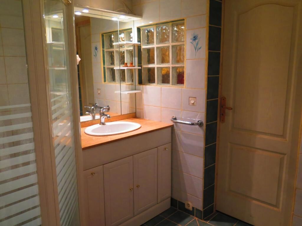A bathroom with a sink, mirror, and a glass shower enclosure.