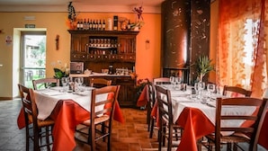 Ein Restaurant mit Holztischen und -stühlen, einer Bar mit Flaschen und Gläsern sowie einem Kamin.
